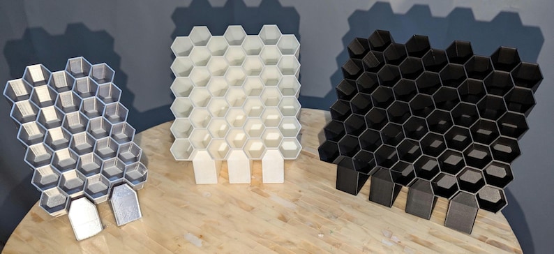 featuring one black ,one white , and one silver posca marker holder.  Showing three different sizes. Front profile