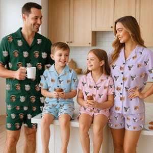 Könnte beinhalten: Familien-Pyjama-Sets in Grün, Hellblau und Rosa, jeweils mit einem sich wiederholenden Muster von Gesichtern. Die Sets bestehen aus kurzärmeligen Hemden mit Knöpfen und Shorts. Eine vierköpfige Familie trägt die Pyjamas, lächelt und hält Cupcakes.