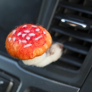 Könnte beinhalten: Ein Filz-Pilz-Lufterfrischer für das Auto mit roter und weißer Kappe und weißem Stiel.