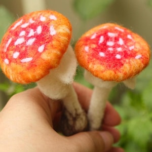 May include: Two felt mushroom ornaments with red and white caps and white stems.