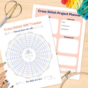 May include: Two printable cross stitch project planners and a WIP tracker are displayed on a wooden surface. The tracker features concentric circles for progress tracking. Scissors, colored pencils, embroidery floss, and a hoop are also visible.
