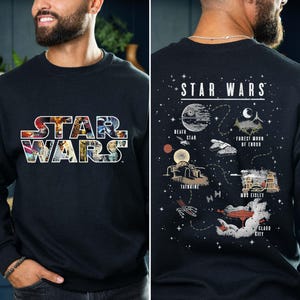 May include: Black sweatshirt featuring the "STAR WARS" logo in a colorful, collage-style design. The back of the sweatshirt has a graphic of the Death Star, Tatooine, and other iconic Star Wars locations.