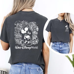 May include: A dark gray t-shirt with a white graphic of Mickey Mouse and various Disney World landmarks. The text "Walt Disney World" is printed below the graphic.