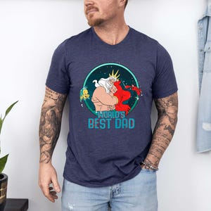 May include: A navy blue t-shirt with a graphic of King Triton and Ariel from The Little Mermaid. The graphic is surrounded by a blue circle with stars and the text "World's Best Dad".