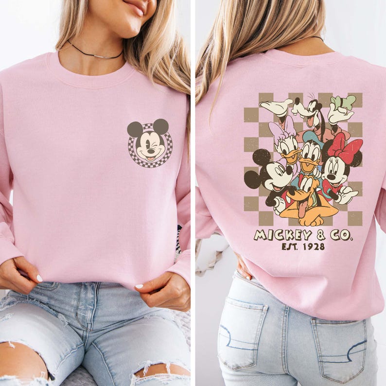 May include: Pink long-sleeved sweatshirt with a Mickey Mouse graphic on the front and a group of Disney characters on the back. The back graphic includes Mickey Mouse, Minnie Mouse, Donald Duck, Goofy, Pluto, and a checkered pattern. The text "Mickey & Co. Est. 1928" is printed below the graphic.