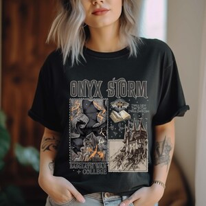 Puede incluir: Camiseta negra con un estampado gr&aacute;fico de un castillo, un murci&eacute;lago, un libro y un cuervo. El texto "ONYX STORM" est&aacute; impreso en blanco en la camiseta. El texto "RAGGATH WAR COLLEGE" est&aacute; impreso en blanco debajo del gr&aacute;fico.