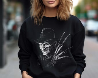 May include: Black sweatshirt featuring a detailed, black and white illustration of a horror movie character with a hat and bladed glove. The design is centered on the front of the crew neck sweatshirt, creating a striking visual.