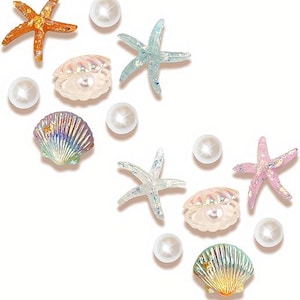 May include: An assortment of ocean-themed embellishments, including orange, blue, and pink starfish, iridescent seashells, and white pearl beads. These decorative elements are arranged on a white background.