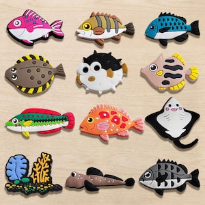 May include: A collection of colorful fish-shaped decorative items. The assortment includes various species in vibrant colors like pink, blue, orange, and green. Each fish has unique patterns and designs, suitable for aquatic-themed decor.