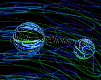Senderos de luz de neón abstractos de color azul y verde alrededor de esferas de vidrio sobre fondo negro