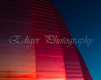 El Centro Kauffman se ilumina con luz roja contra un cielo azul profundo