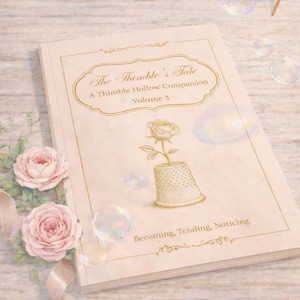 Pode incluir: Um livro intitulado "The Thimble's Tale, A Thimble Hollow Companion, Volume 3" com uma ilustração de rosa. Rosas cor-de-rosa e uma fita estão à esquerda. Bolhas e um pequeno frasco de vidro com tampa de cortiça ao fundo.