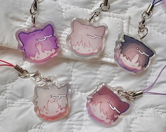 May include: A collection of five clear acrylic charms with cartoon character designs. Each charm features a different color scheme, including purple, pink, and blue, with a silver-colored clasp and a matching lanyard.