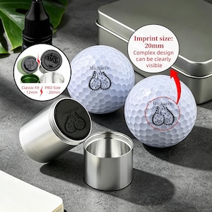 May include: Two white golf balls with dimpled surfaces, each featuring a black graphic of testicles and the text Michael's. Two cylindrical metal containers are present, one with a black lid showing the same graphic and text, and a metal tin.