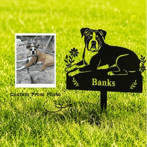 May include: A black metal dog sign with the name "Banks" on it, featuring a silhouette of a dog. The sign is decorated with floral and leaf accents. A photo of a dog is in the upper left corner. The text "Custom From Photo" is below the photo.