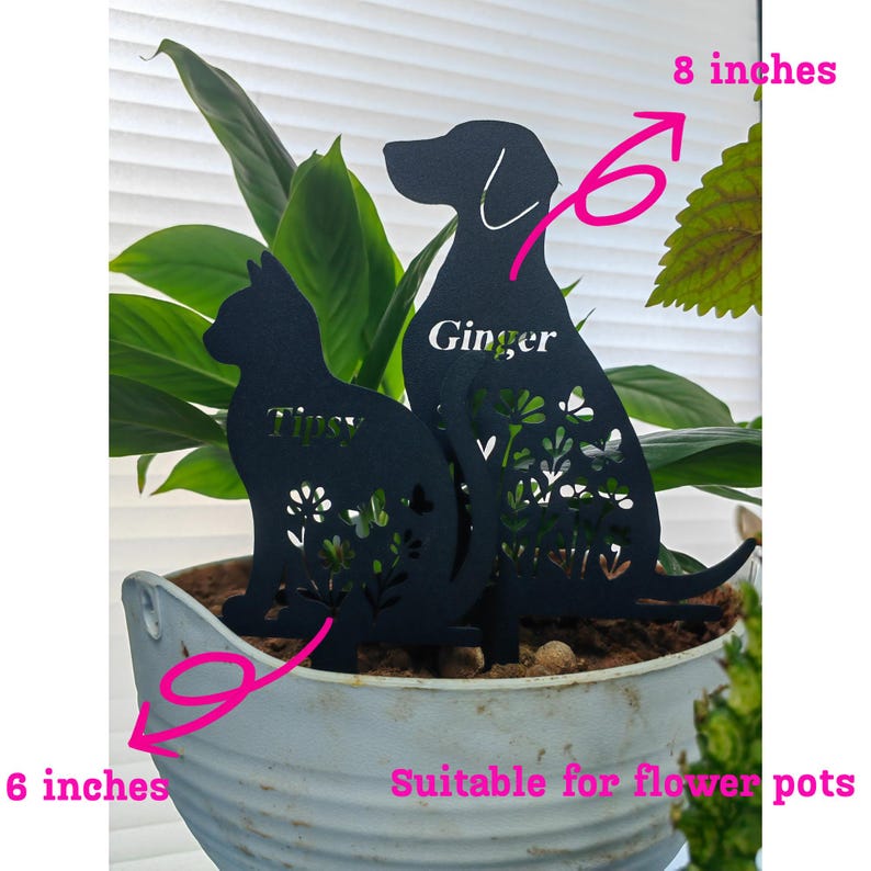 May include: Black metal cat and dog silhouette plant stakes. The dog stake is 8 inches tall and the cat stake is 6 inches tall. The dog is labeled "Ginger" and the cat is labeled "Tipsy". Both stakes have floral and butterfly cutouts.