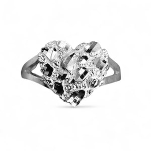 May include: A silver ring with a heart-shaped design. The heart is textured with multiple facets, creating a sparkling effect. The band is a simple, smooth silver. The ring is displayed against a white background.