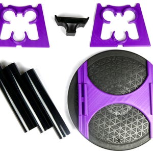 May include: An assortment of disassembled exercise equipment components. The parts include purple plastic supports, black plastic tubes, and a black circular base with a purple frame. The components are arranged on a white surface.