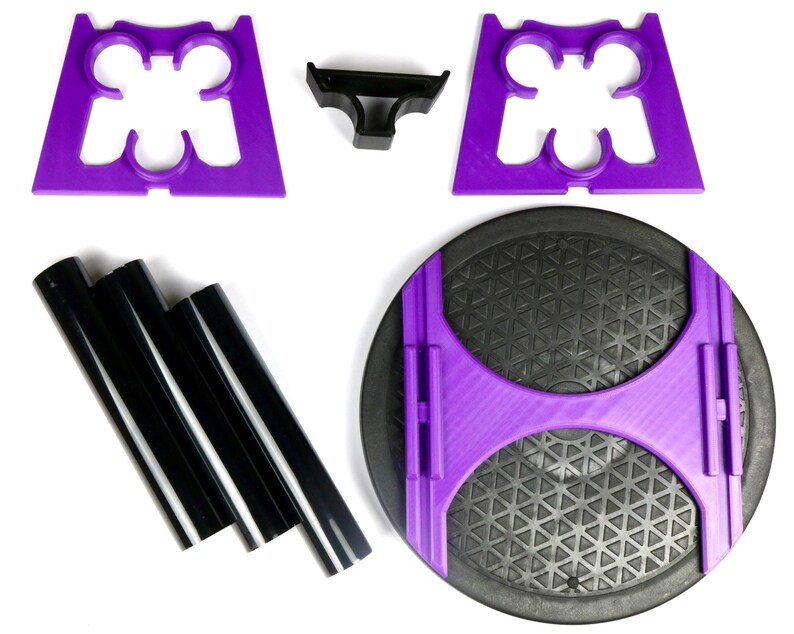 May include: An assortment of disassembled exercise equipment components. The parts include purple plastic supports, black plastic tubes, and a black circular base with a purple frame. The components are arranged on a white surface.