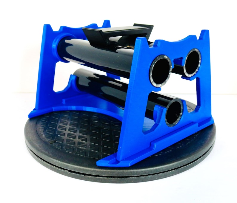 May include: A blue wine bottle holder with a black base. The holder is designed to hold two bottles horizontally. The holder is made of plastic and has a modern design. The holder is on a black, circular base.