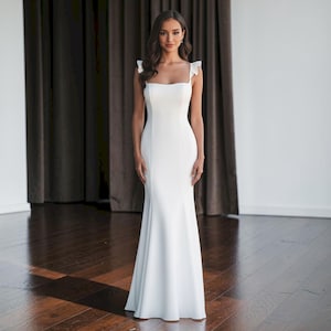 モダンなフリル キャップ スリーブ ウェディング ドレス、ボタン バック トレーン付きのミニマルなクレープ シース ブライダル ガウン、シンプルでエレガントなスクエア ネック ウェディング ドレス。