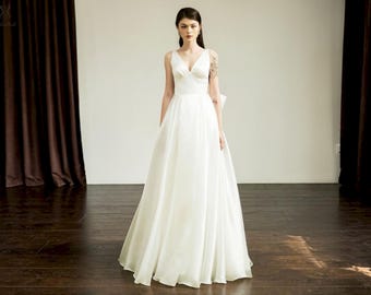 Vestido de noiva simples em linha A, cintura império, laço nas costas, estilo minimalista de conto de fadas.