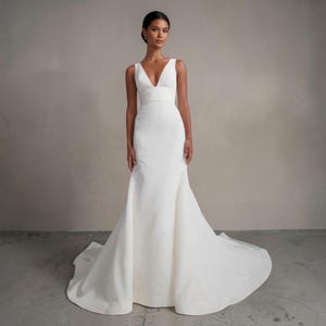 Vestido de novia corte sirena con detalle de lazo, vestido de novia sencillo y elegante con tirantes anchos, vestido de novia minimalista con cola de capilla.
