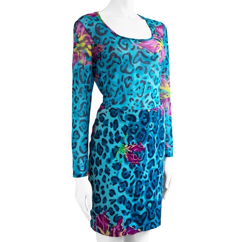 K&ouml;nnte beinhalten: Ein blaues Netzkleid mit Leopardenmuster und floralen Akzenten. Das Kleid hat lange &Auml;rmel und einen runden Ausschnitt.