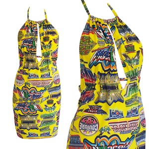 Puede incluir: Vestido amarillo de tirantes con un diseño de corte y un estampado colorido de varios logotipos y texto. El vestido tiene una silueta ajustada y una longitud corta.