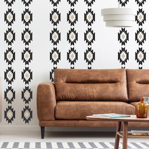 May include: A brown leather sofa with a white wall behind it. The wall has a repeating pattern of black and beige geometric shapes.
