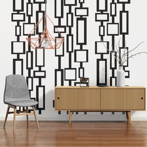 May include: A mid-century modern living room with a geometric black and white patterned wallpaper, a light wood cabinet with two doors, a gray chair, and a copper wire cage pendant light.