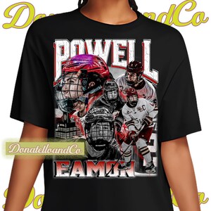 May include: Black t-shirt with a graphic of hockey players wearing red and white jerseys. The text "POWELL EAMON" is printed on the shirt.