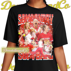 May include: Black t-shirt featuring a collage of softball players in red uniforms, with the name "SAM LANDRY" in large red letters at the top. The word "SOFTBALL" is printed in red at the bottom.
