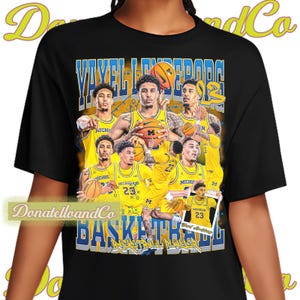 May include: Black t-shirt featuring a basketball design with the text "Yavell LeSeurda" and "Basketball". The design includes images of basketball players in yellow uniforms with the word "Michigan" on them.