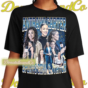 May include: Black t-shirt featuring a collage of images of Andraya Carter, with the text "ANDRAYA CARTER SPORTS COMMENTATOR" in blue and white. The shirt has a vintage, retro design with a gold and blue background.