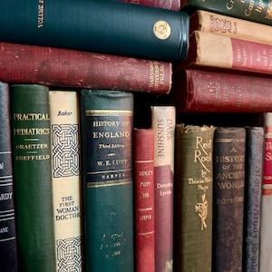 May include: A collection of antique books with various colors and titles. The spines are visible, showcasing titles like "Practical Pediatrics" and "History of England." The books are stacked and arranged, creating a vintage aesthetic.