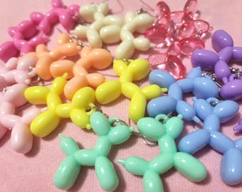 May include: A collection of colorful balloon dog charms in various shades, including pink, orange, yellow, green, blue, and purple. The charms are made of plastic and have a metallic loop for attaching to jewelry or other items.
