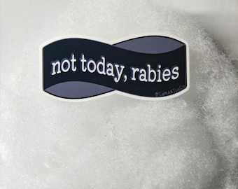 以下が含まれることがあります： 黒とグレーのバナーデザインに白いフォントで「not today, rabies」と書かれたステッカー。ステッカーは白い縁取りがあり、ふわふわの白い背景に配置されています。