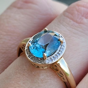 Precioso anillo de circonita azul ovalada y diamantes de alta calidad engastado en oro amarillo. Hermoso diseño de filigrana. Talla 6.5