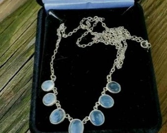 Puede incluir: Un collar de plata con una cadena y siete piedras azules de forma ovalada.