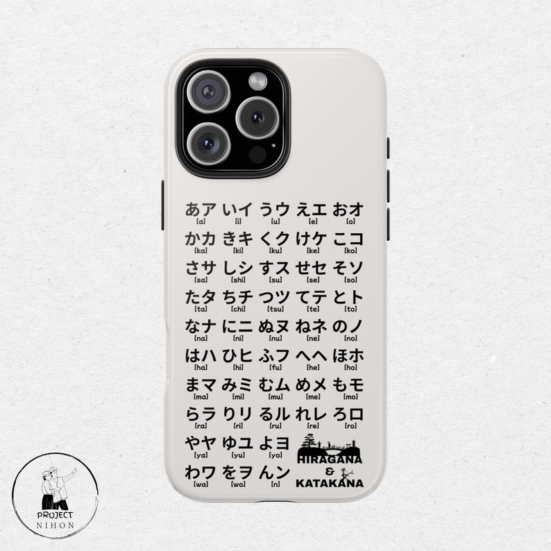 May include: A white phone case with black text showing the Japanese alphabet, Hiragana and Katakana. The text includes the pronunciation of each character in brackets.