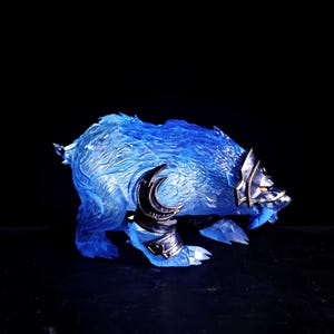 以下が含まれることがあります： 獰猛な表情をした青と銀の狼の置物。狼は半透明の素材でできており、霜降り状の外観になっています。