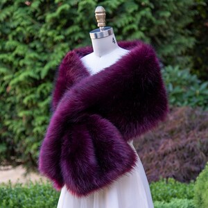 May include: A deep purple faux fur shawl, draped over a white dress form. The shawl is soft and fluffy, and would be a great addition to any winter wardrobe.