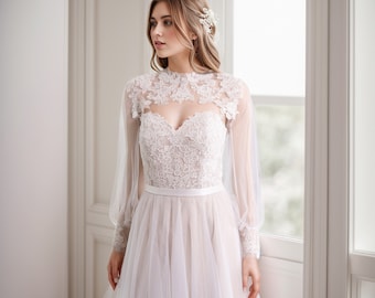 May include: A white floor-length gown featuring a sweetheart bodice with intricate floral lace overlays, long sheer tulle sleeves with lace cuffs, a high illusion neckline, and a smooth waistband. The skirt is made of layered tulle fabric.