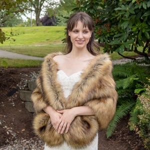 May include: A woman wearing a brown faux fur shawl over a white lace wedding dress. The shawl has a long, flowing design and is made of soft, plush faux fur.