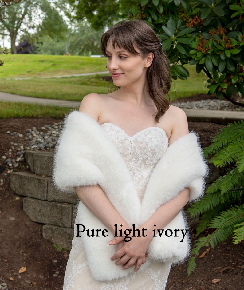 May include: A white faux fur shawl draped over a person wearing a white lace dress. The text "Pure light ivory" is visible in the image.