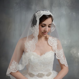 Pode incluir: Um v&eacute;u de noiva branco com uma delicada renda. O v&eacute;u &eacute; feito de tule macio e tem uma borda festonada. A renda &eacute; intrincada e detalhada, com um padr&atilde;o floral.