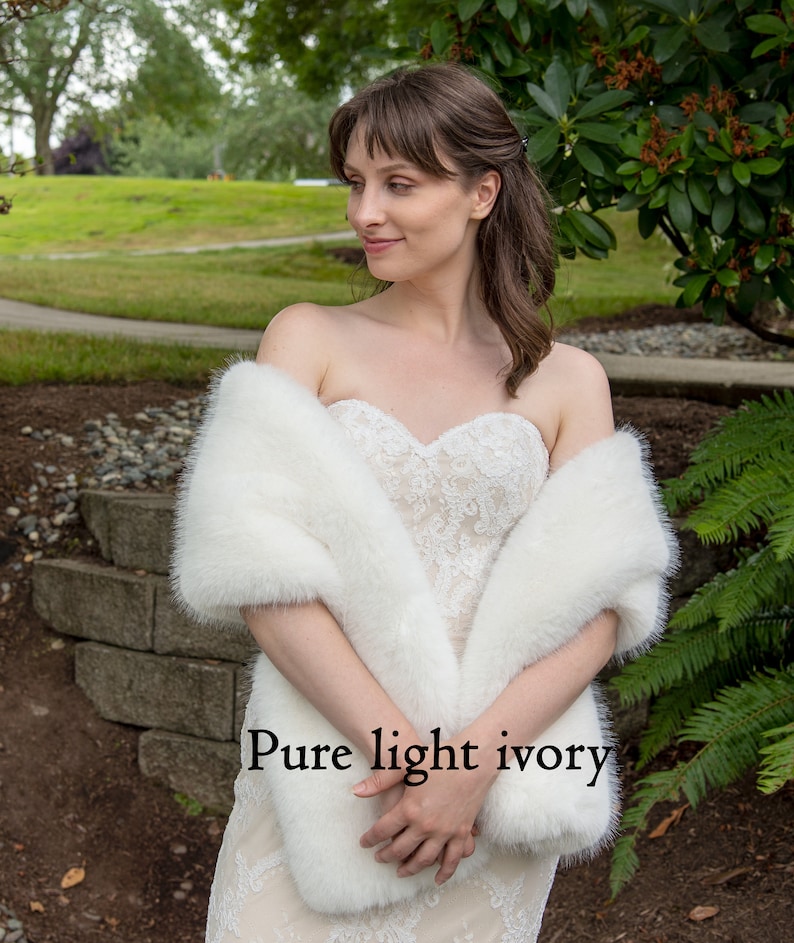 May include: A white faux fur shawl draped over a person wearing a white lace dress. The text "Pure light ivory" is visible in the image.