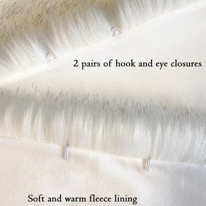 May include: Close-up of a white faux fur fabric with two pairs of hook and eye closures. The fabric is lined with a soft and warm fleece lining.
