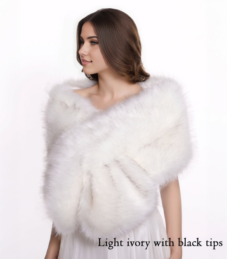 May include: A white faux fur shawl with black tips. The shawl is draped over a person's shoulders.